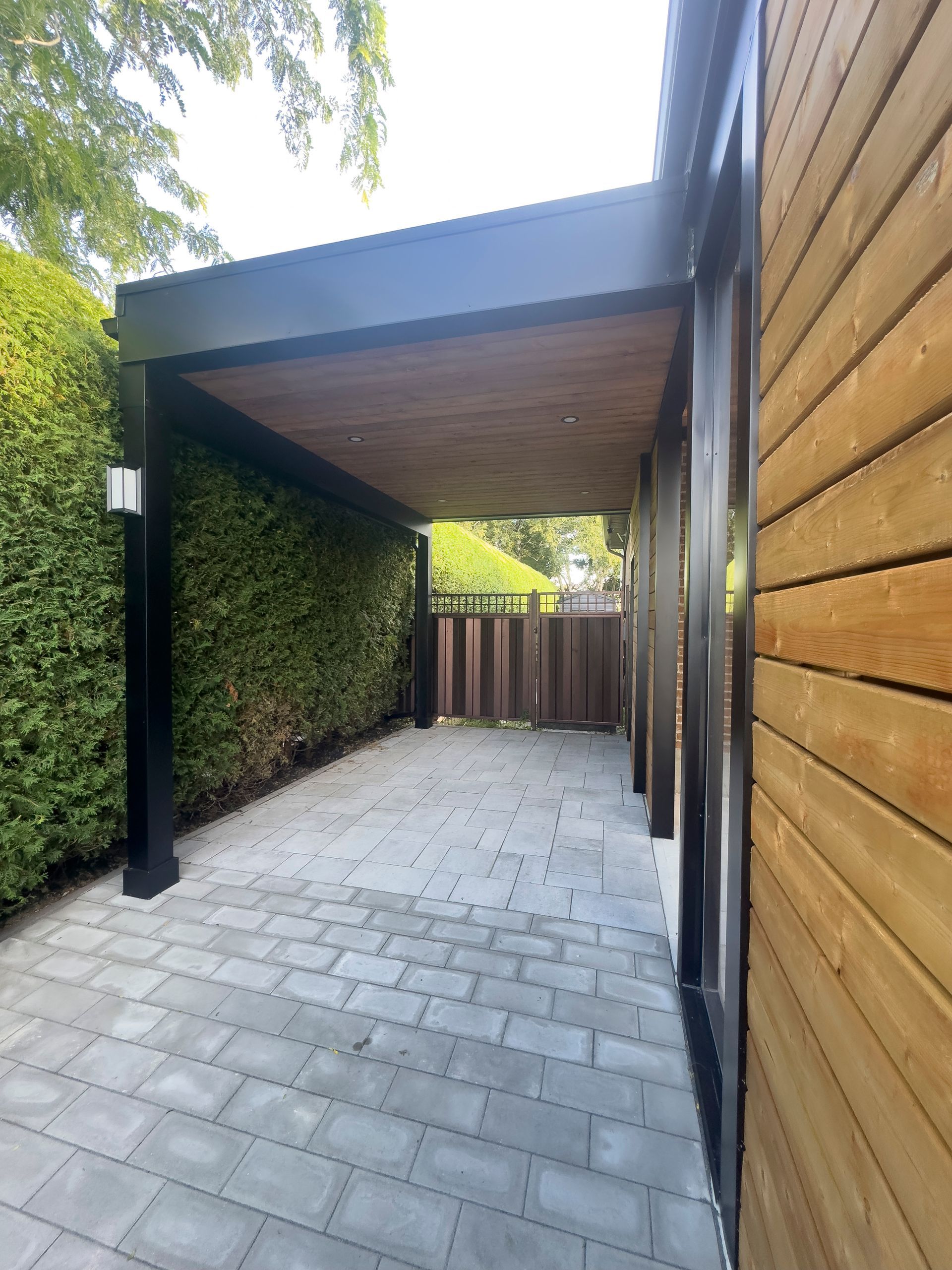 Un abri voiture avec un toit en bois se trouve à côté d'une maison.