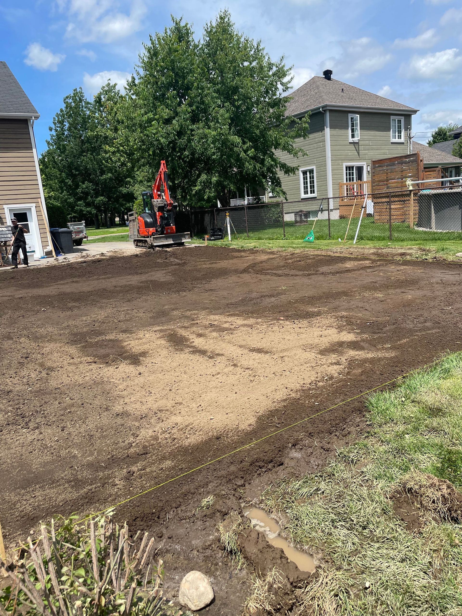 Un grand champ de terre avec une maison en arrière-plan.