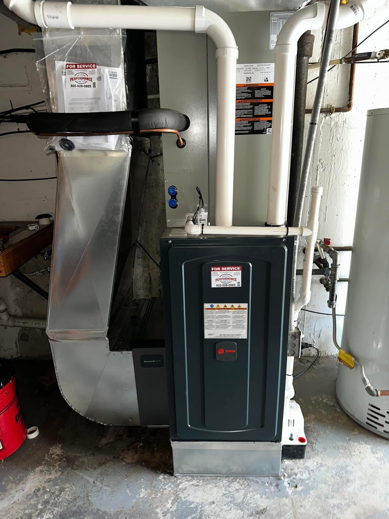 A gas furnace is sitting in a basement next to a water heater.