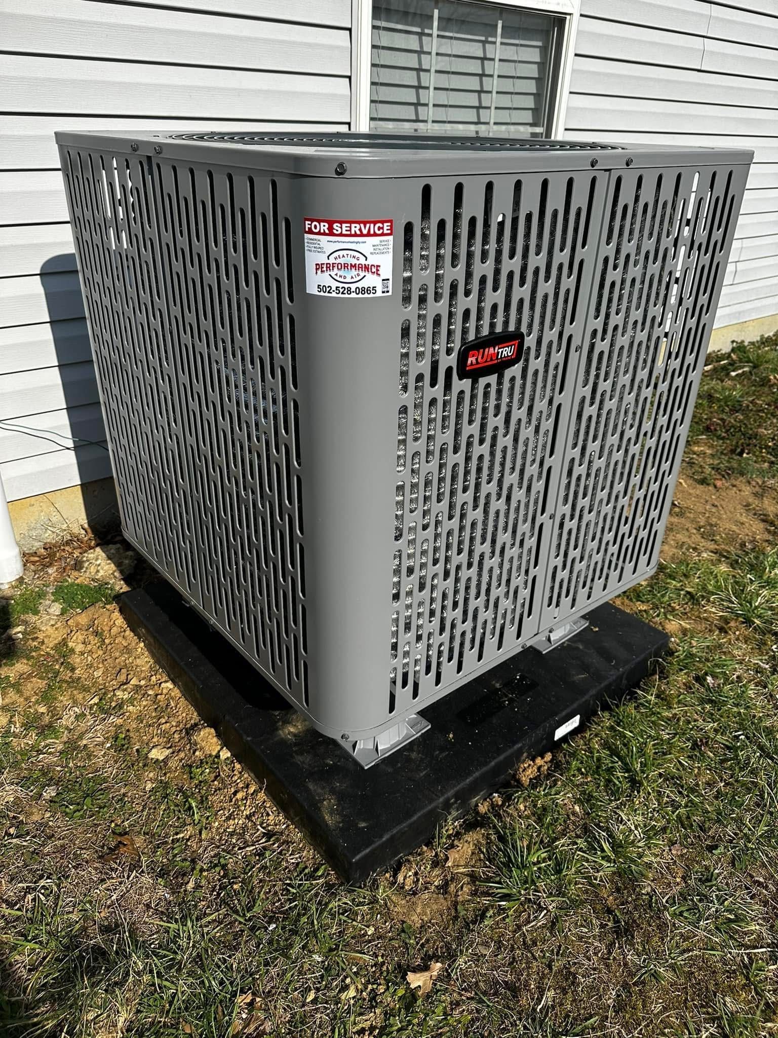 A large air conditioner is sitting on the ground in front of a house.