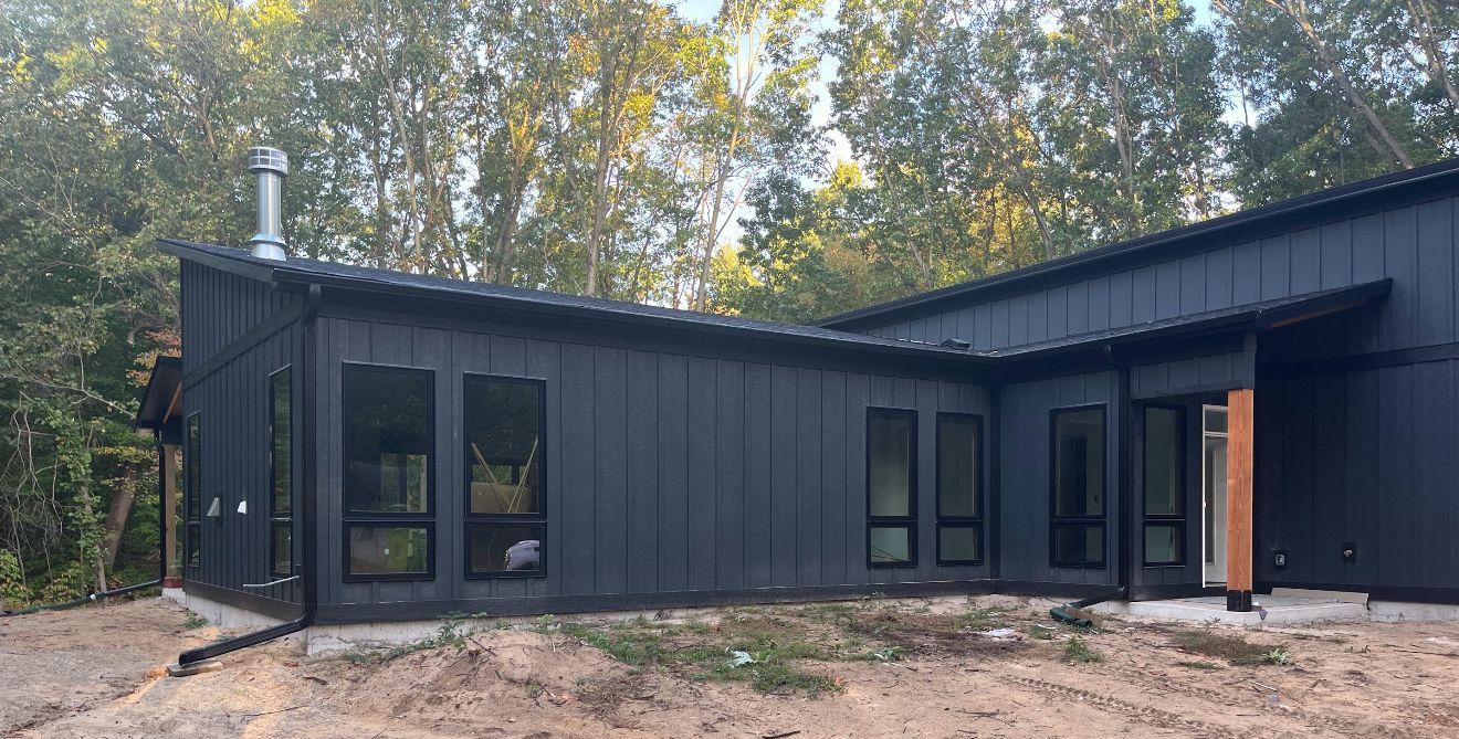 Beige house exterior with gutters and downspout against a blue sky.