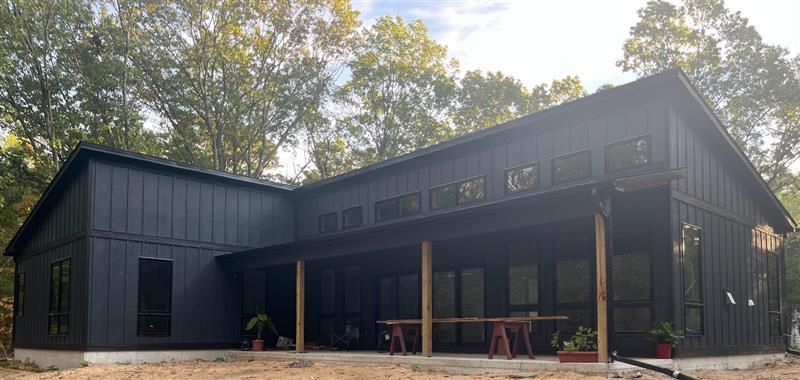 Construction worker in yellow hard hat and vest inspecting a doorway, holding clipboard.