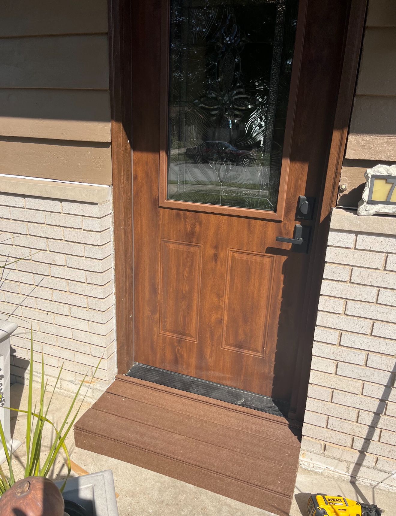 A person power washing a house. Green grass, trees, and sky in the background.