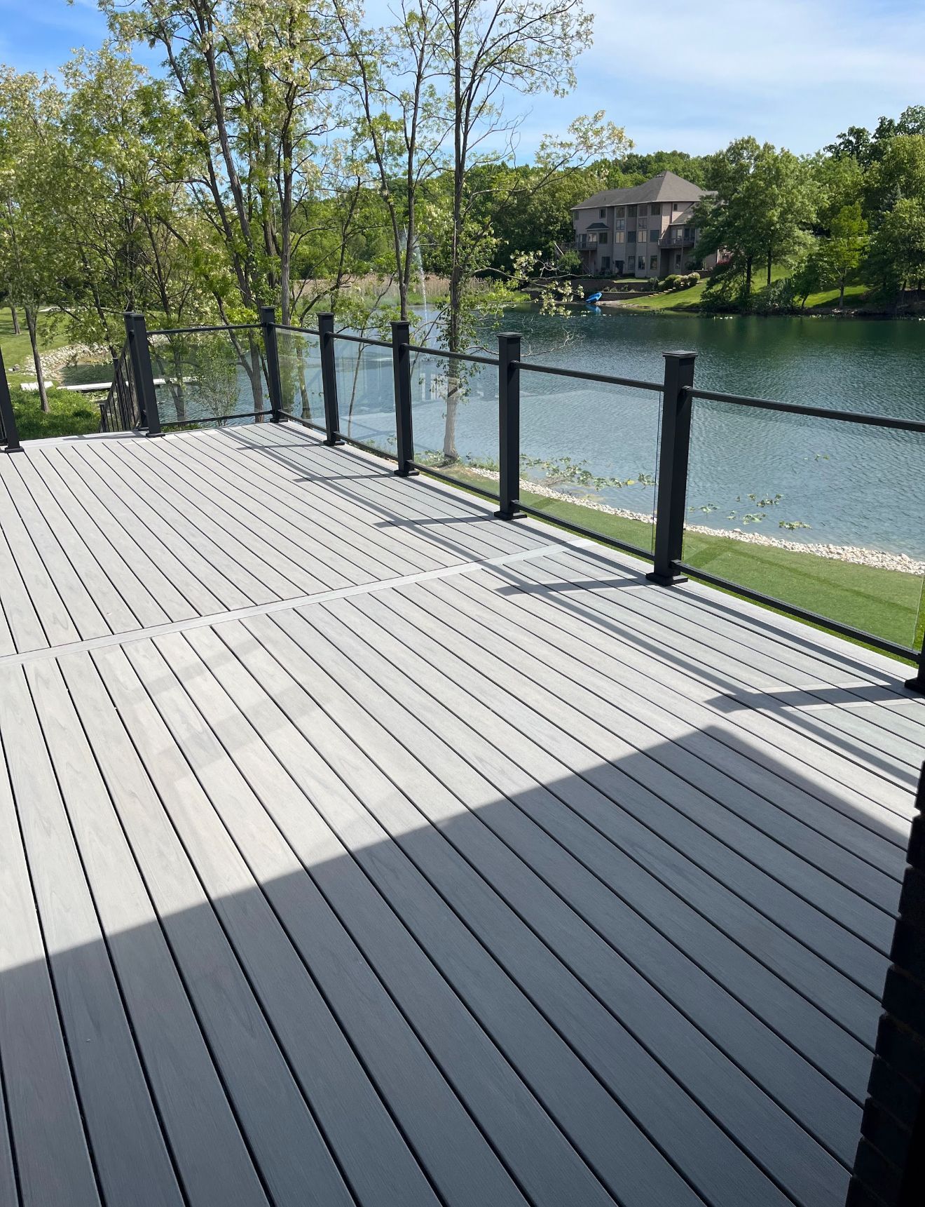 A person power washing a house. Green grass, trees, and sky in the background.