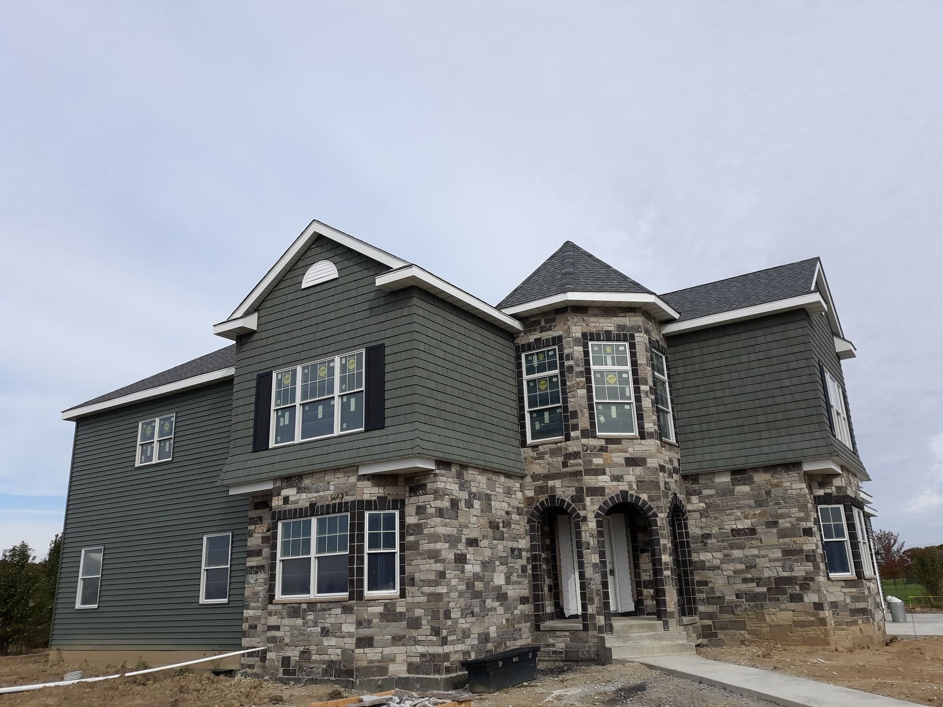 Man on ladder power washing a roof against a blue sky.