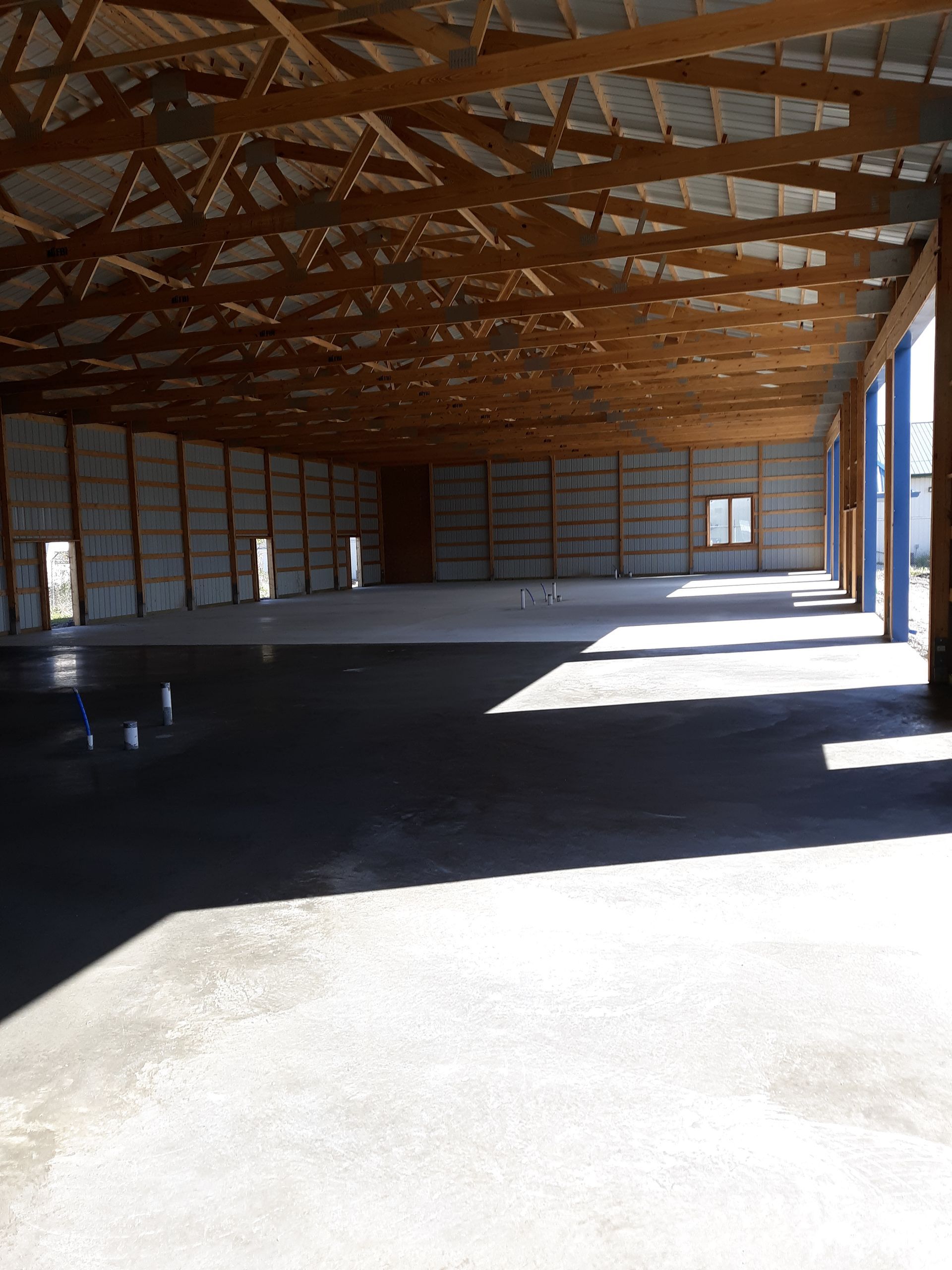A person power washing a house. Green grass, trees, and sky in the background.