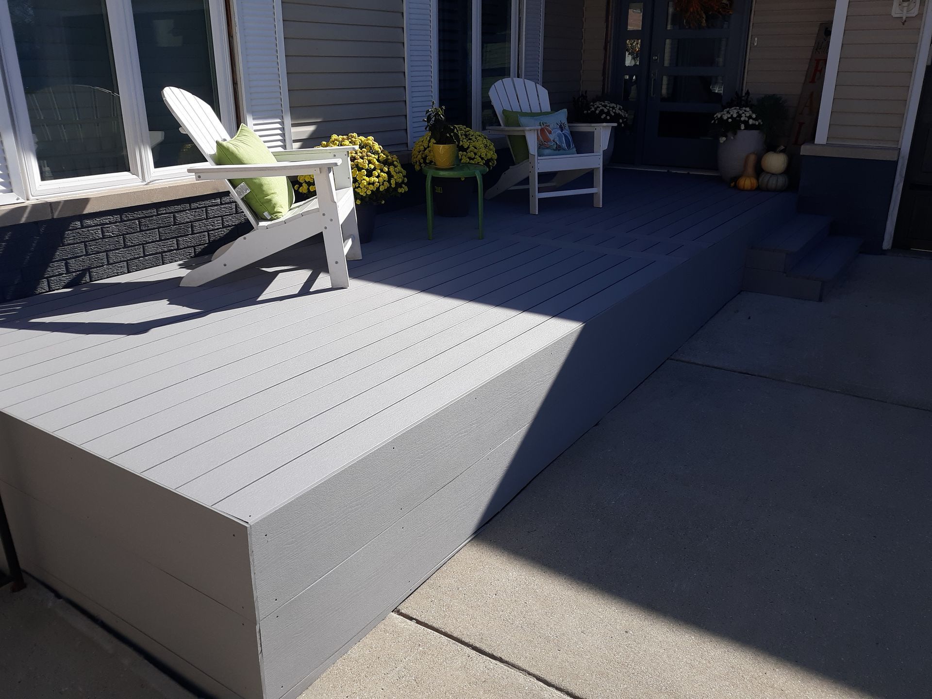 Beige gutters on a house with gray siding and a black shingled roof, against a blue sky.