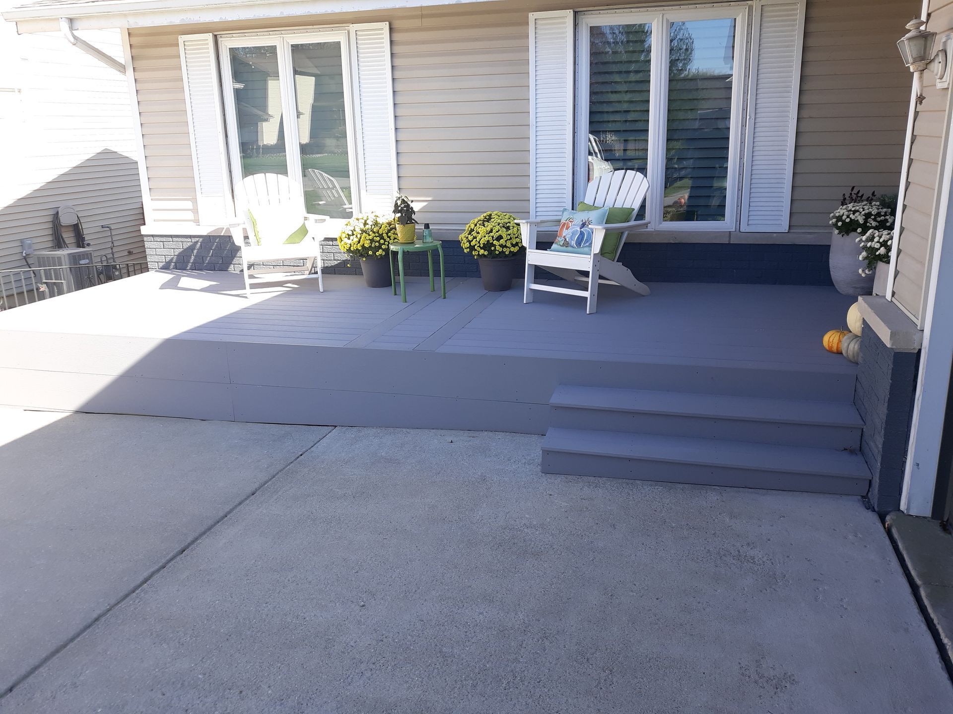 Two construction workers installing siding on a building, both wearing orange shirts and tool belts.
