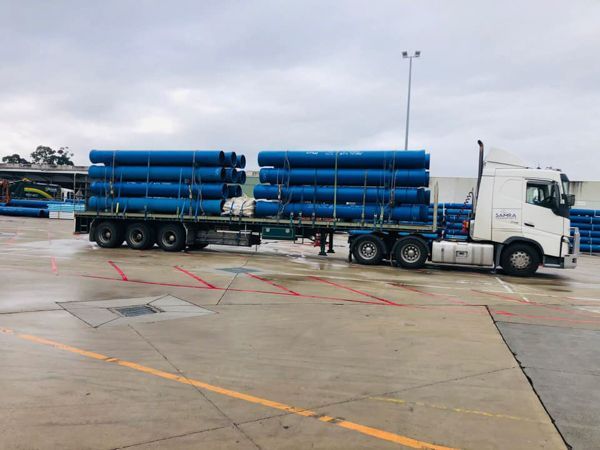 A semi truck is carrying a load of blue pipes.