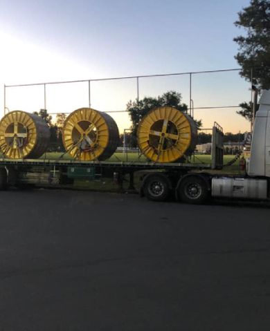 A truck is carrying large yellow spools of wire