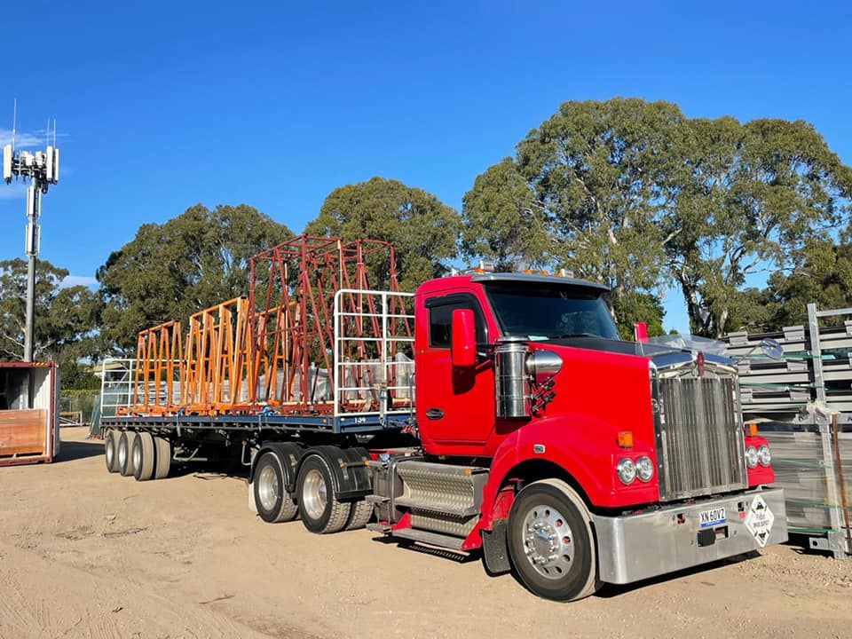 A red semi truck is parked in a dirt lot.