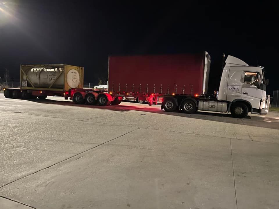 A semi truck is parked in a parking lot at night.