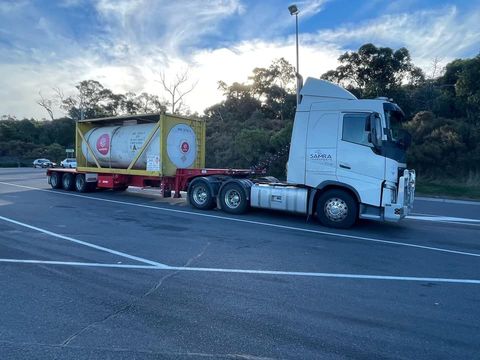 A semi truck is driving down a road with a trailer attached to it.