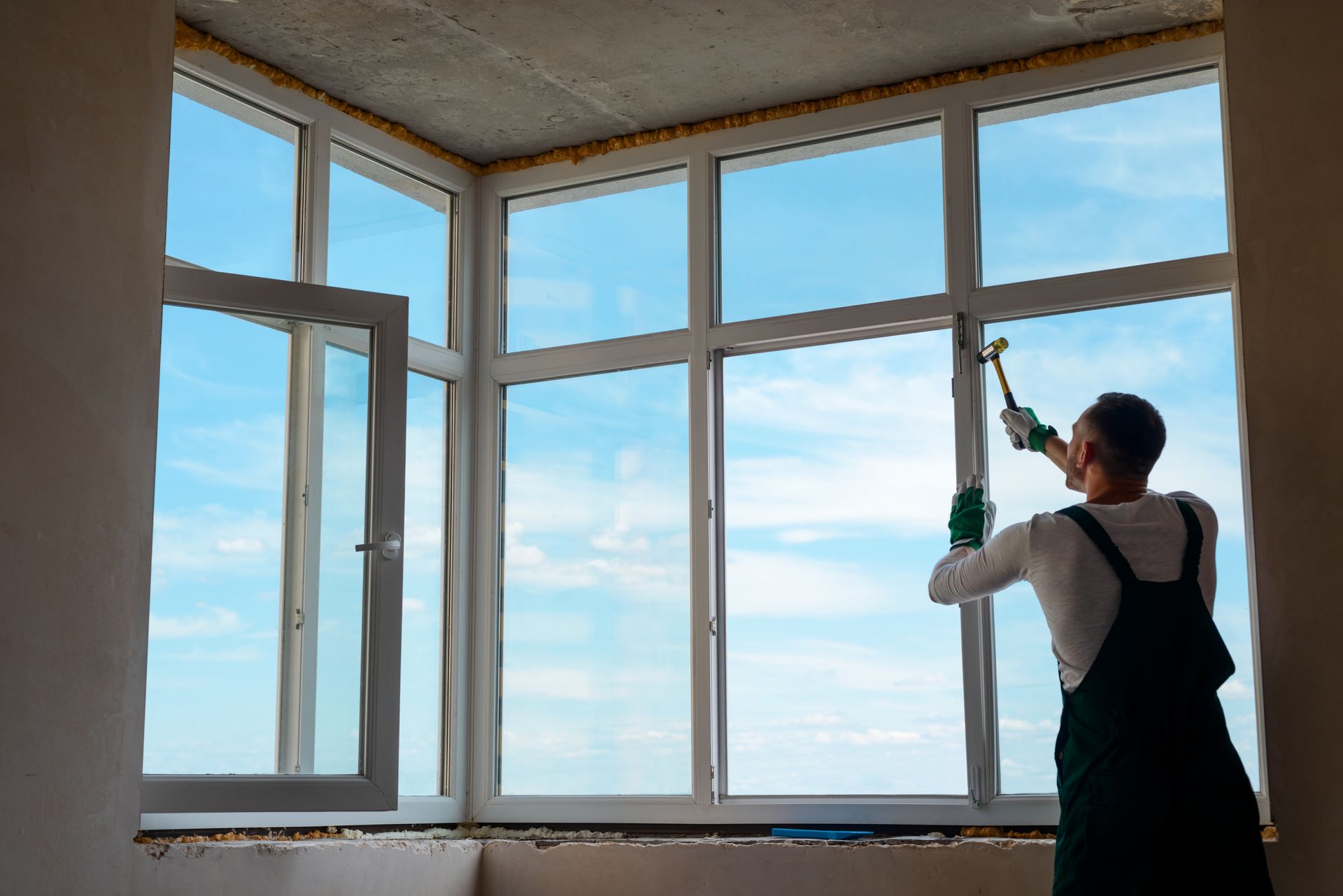 Person cleaning a large window with a squeegee in a bright room overlooking the sky