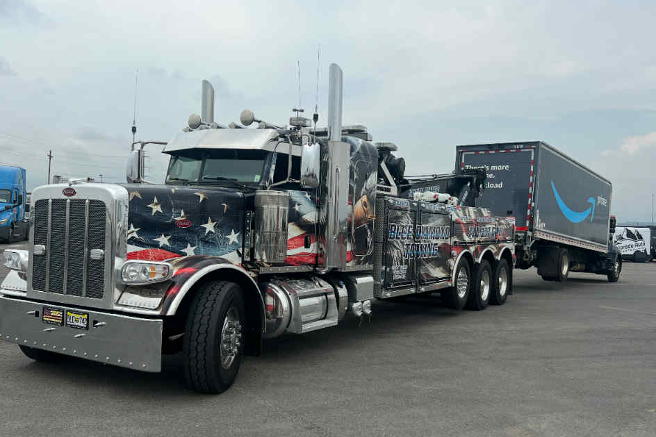 American flag-themed semi-truck with tow unit attached to an Amazon trailer parked in a lot.