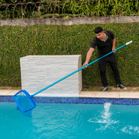 a man is cleaning a swimming pool with a net .