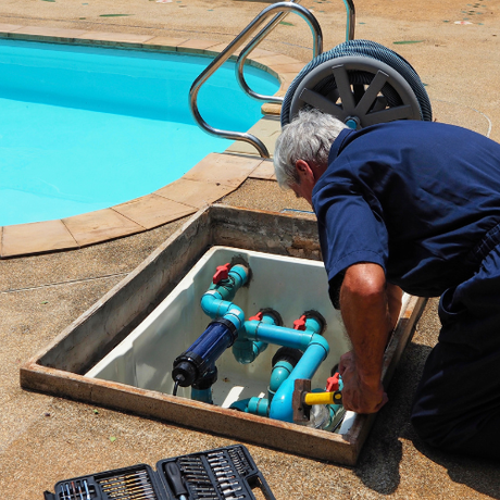a man in a blue jumpsuit is working on a swimming pool
