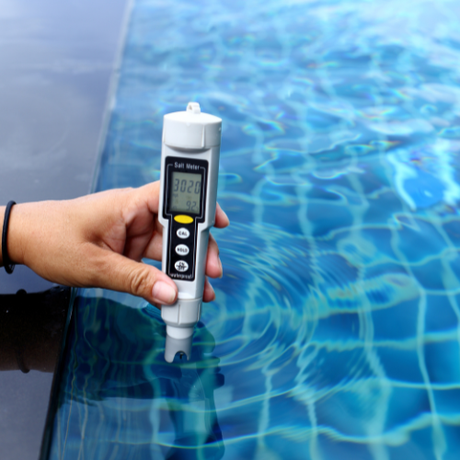 a person is holding a digital thermometer in front of a swimming pool .