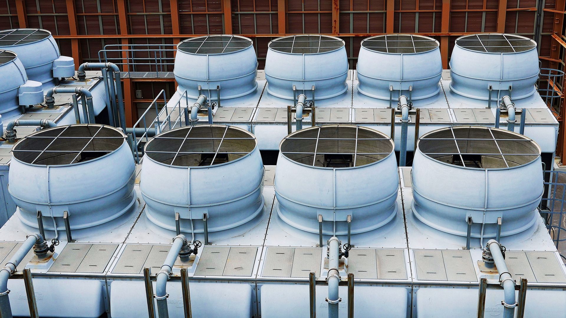 Industrial cooling towers, white with rounded tops, arranged in rows.