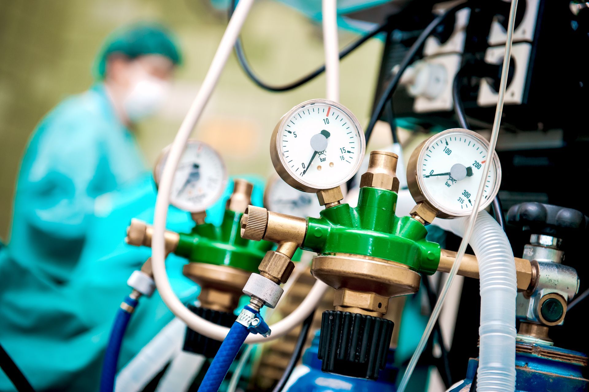 Medical equipment with gauges in an operating room, a surgeon in scrubs in the background.