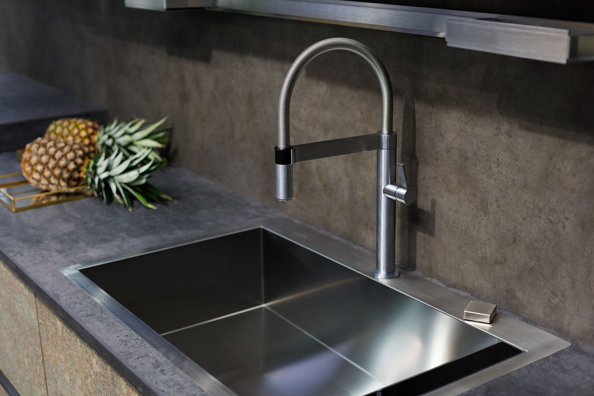 A kitchen sink with a faucet and pineapples on the counter