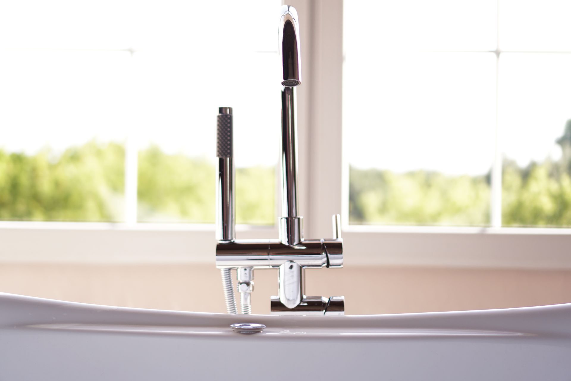 A bathtub with a faucet and a window in the background.