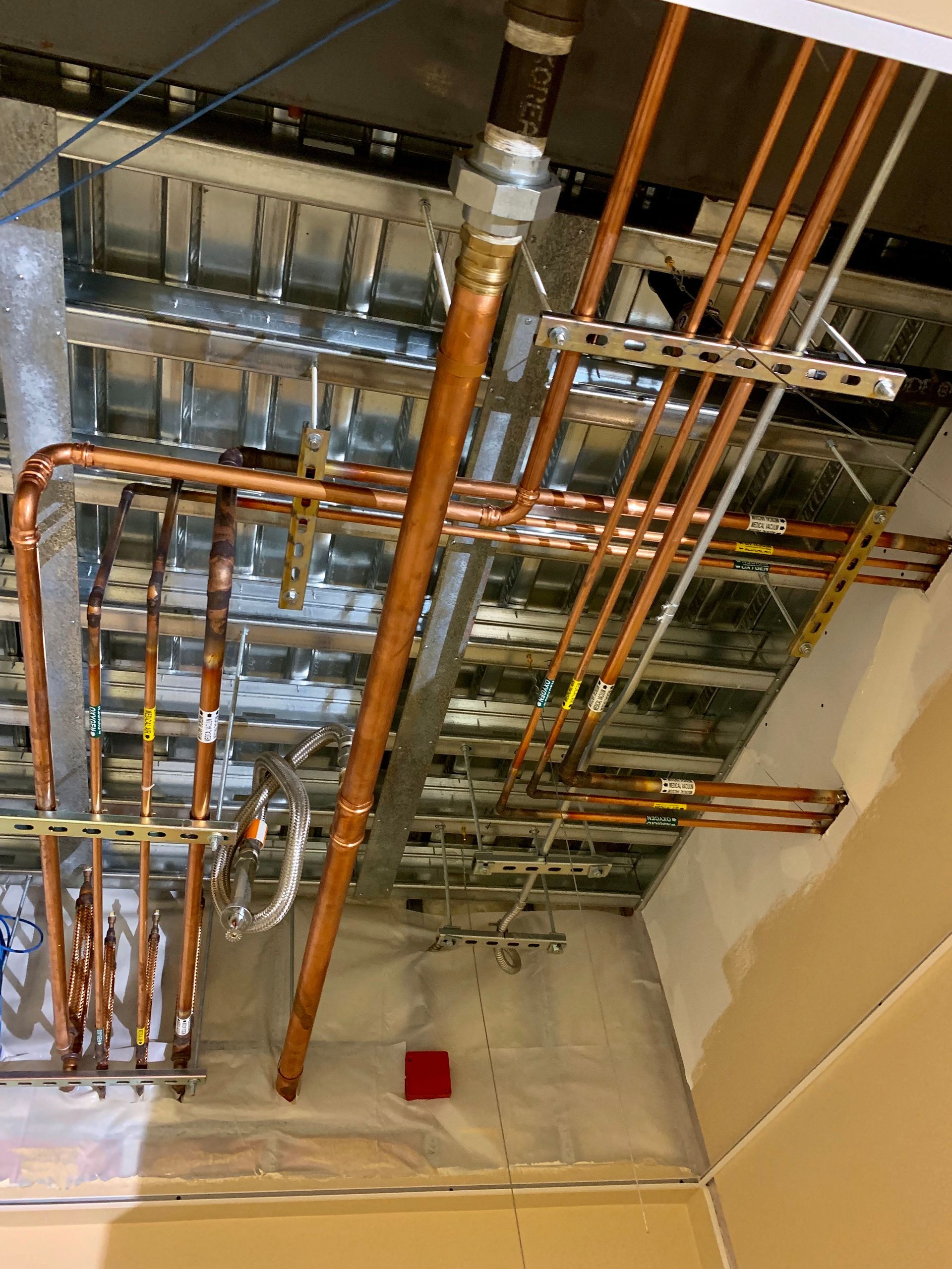A bunch of copper pipes are hanging from the ceiling of a building.