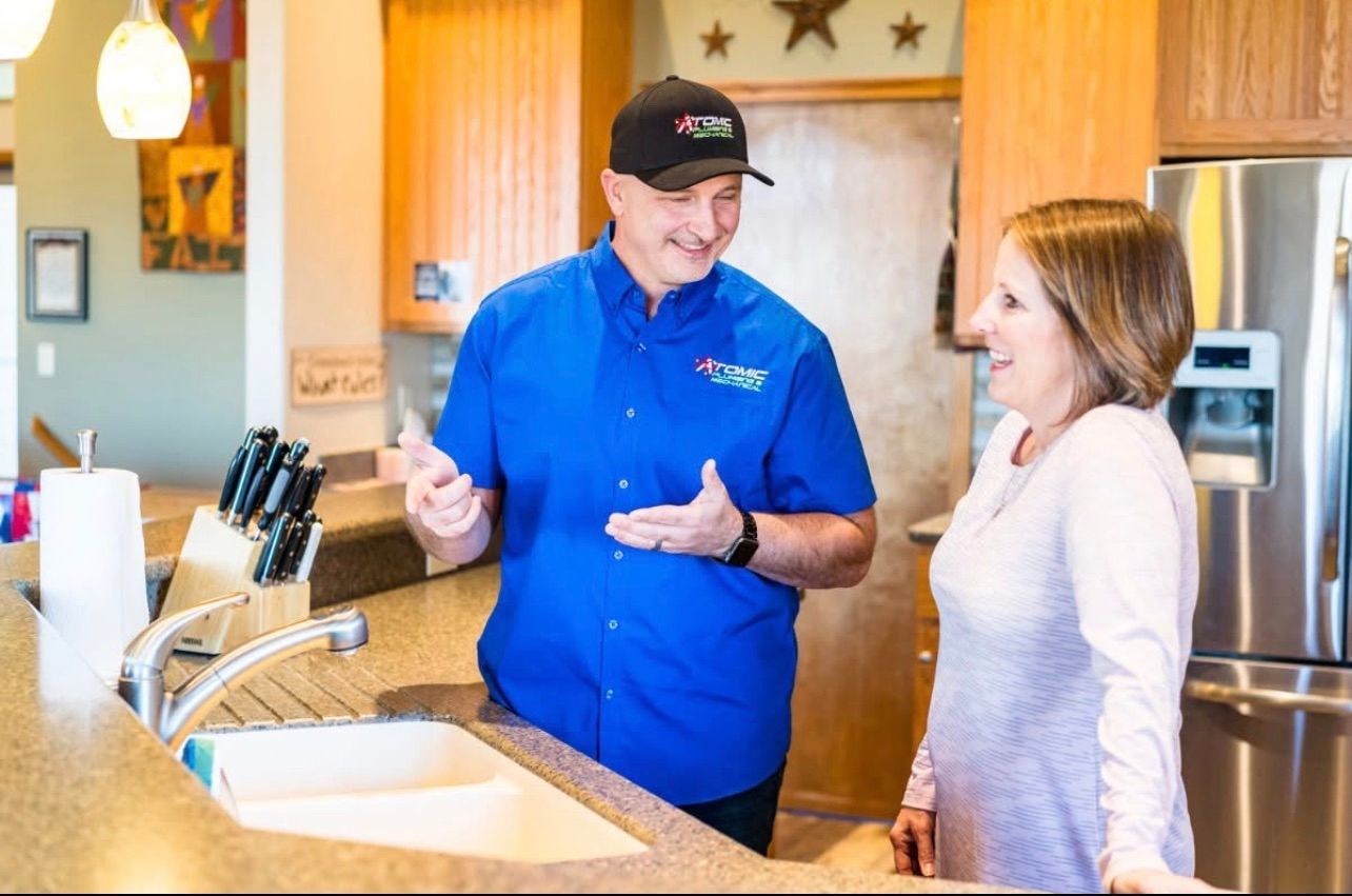 A man in a blue shirt is talking to a woman in a kitchen.