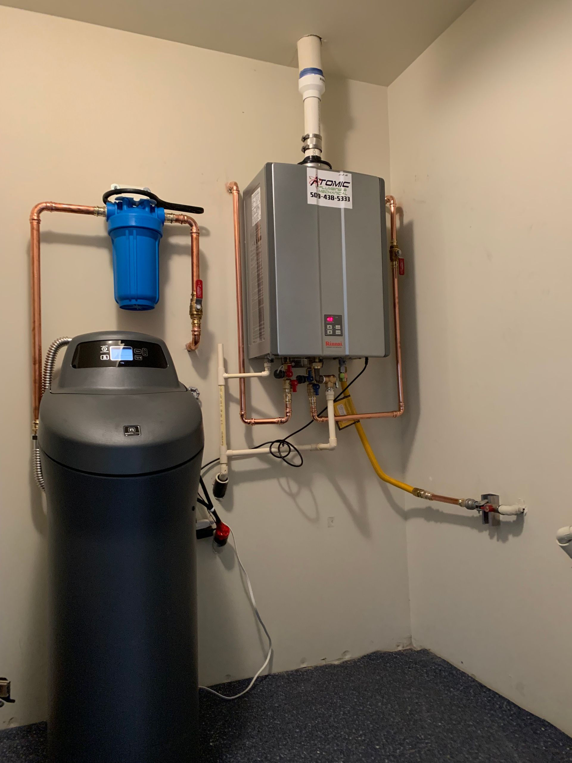 A room with a water heater and a water filter on the wall.