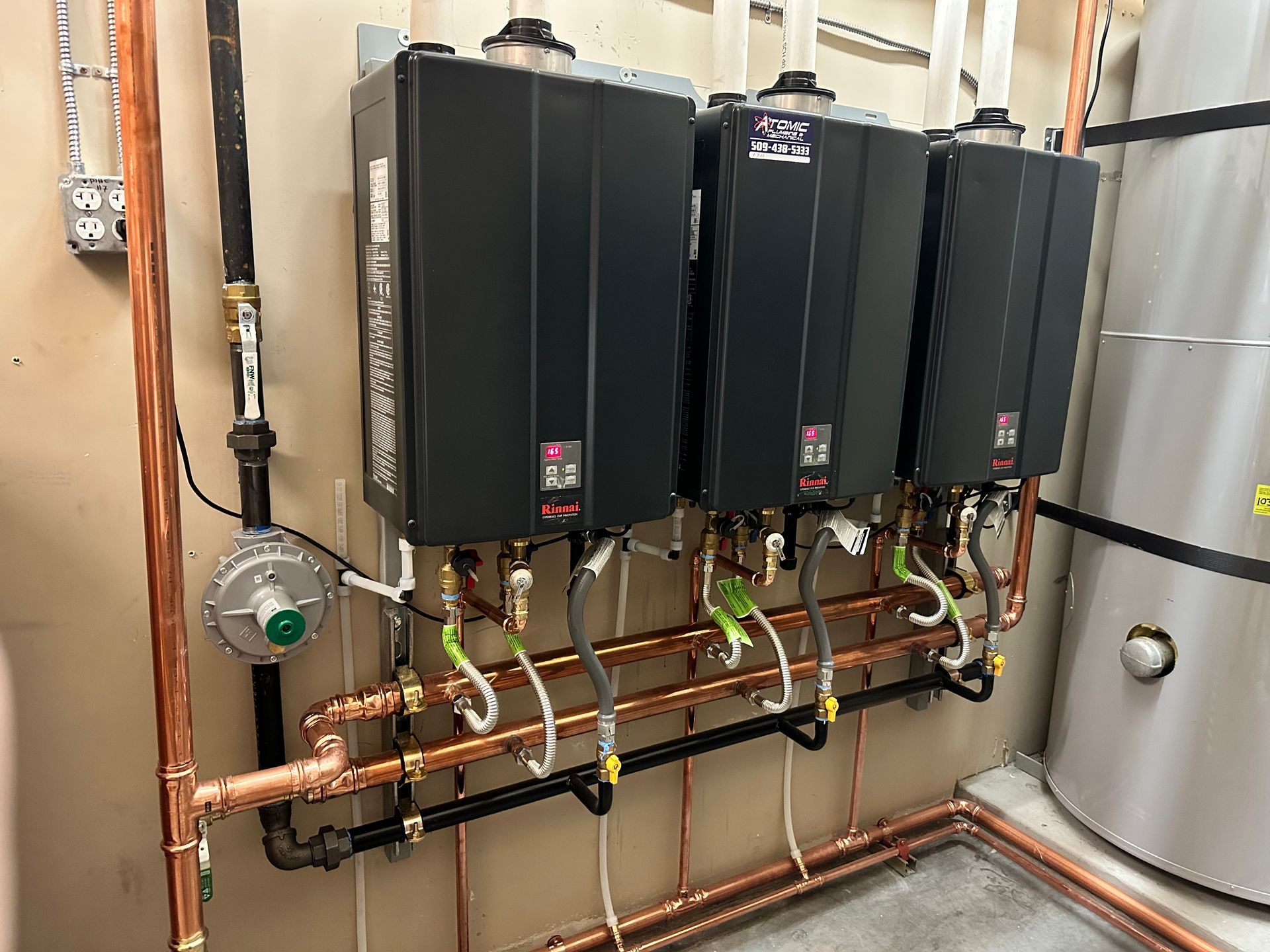 A row of water heaters are lined up next to each other on a wall.