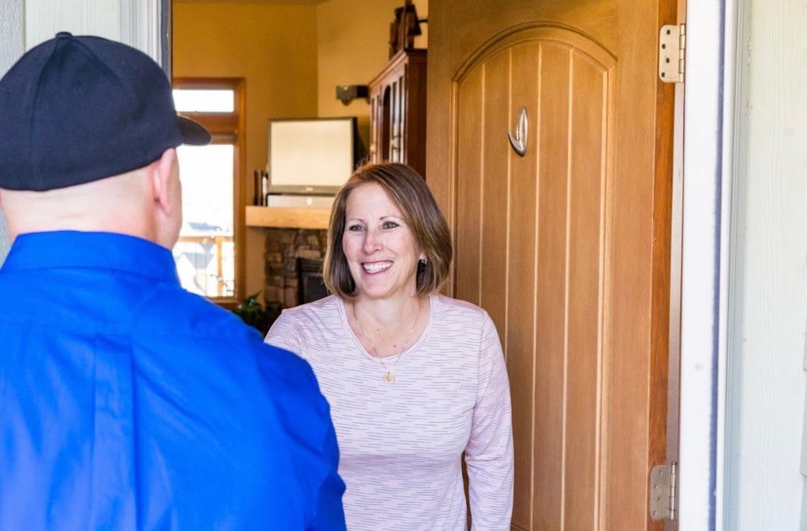 A man in a blue shirt is talking to a woman in a doorway.