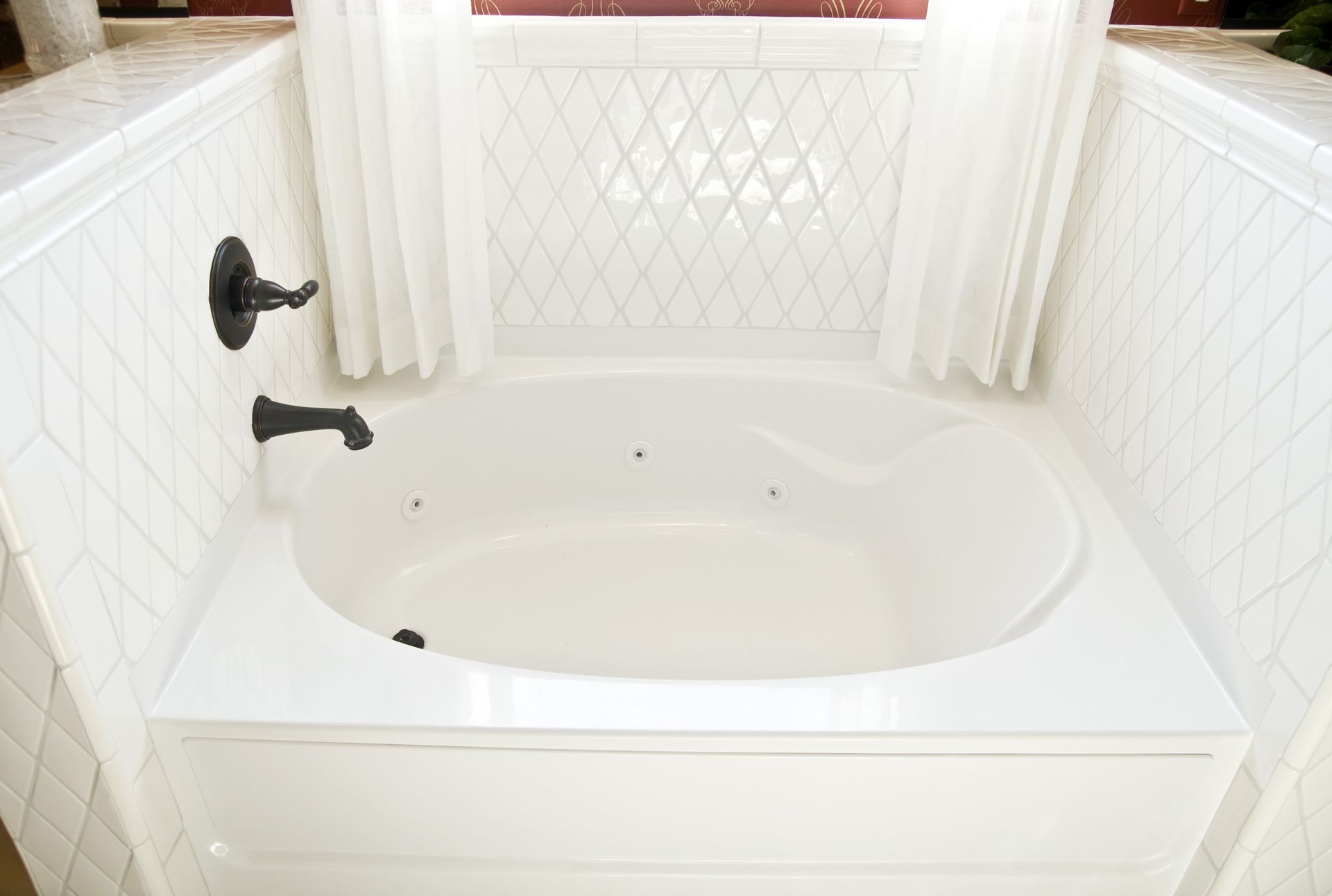 A white bathtub in a bathroom next to a window.