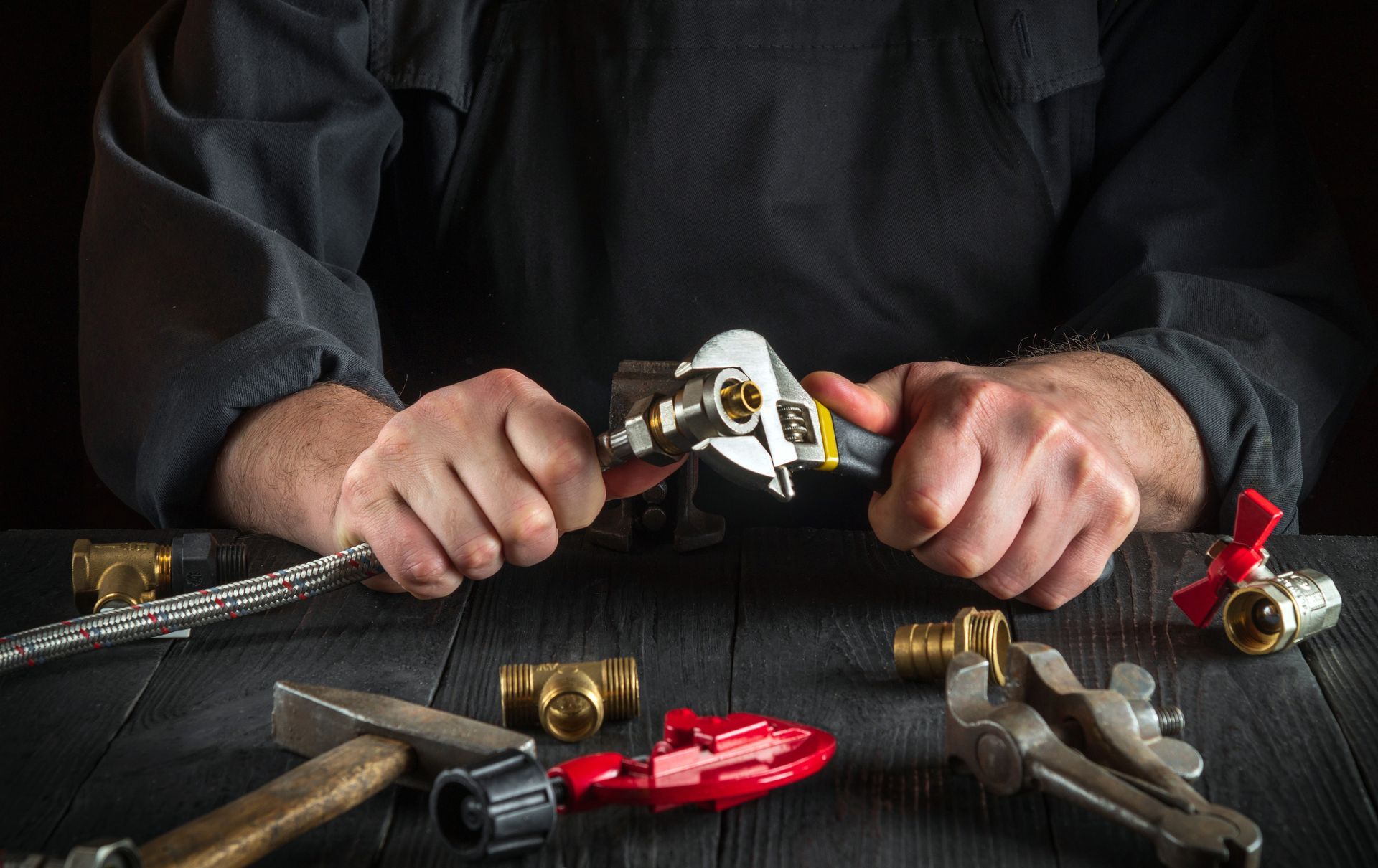 A plumber is working on a pipe with a wrench.