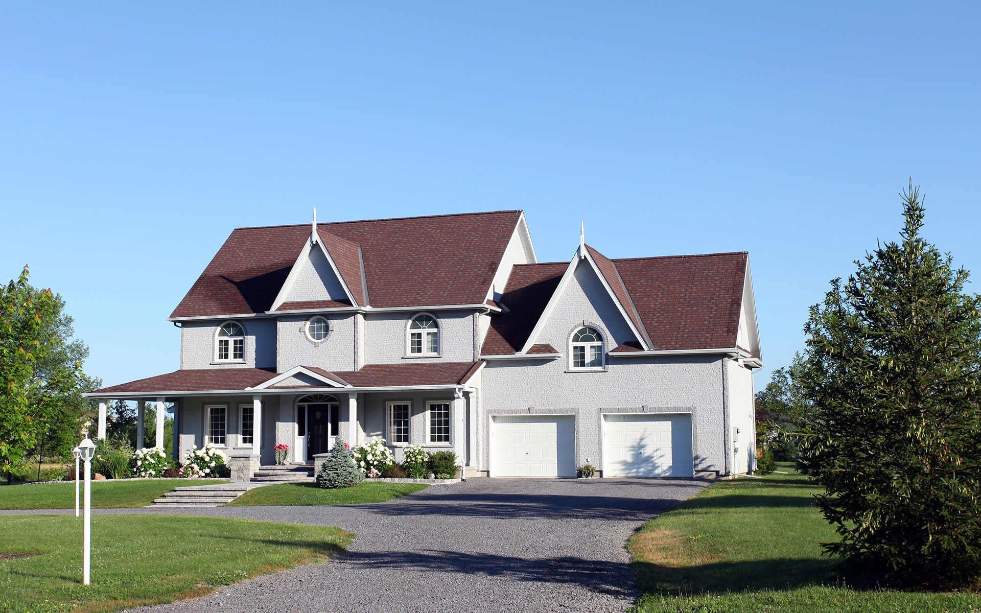 A large white house with a brown roof and two garages