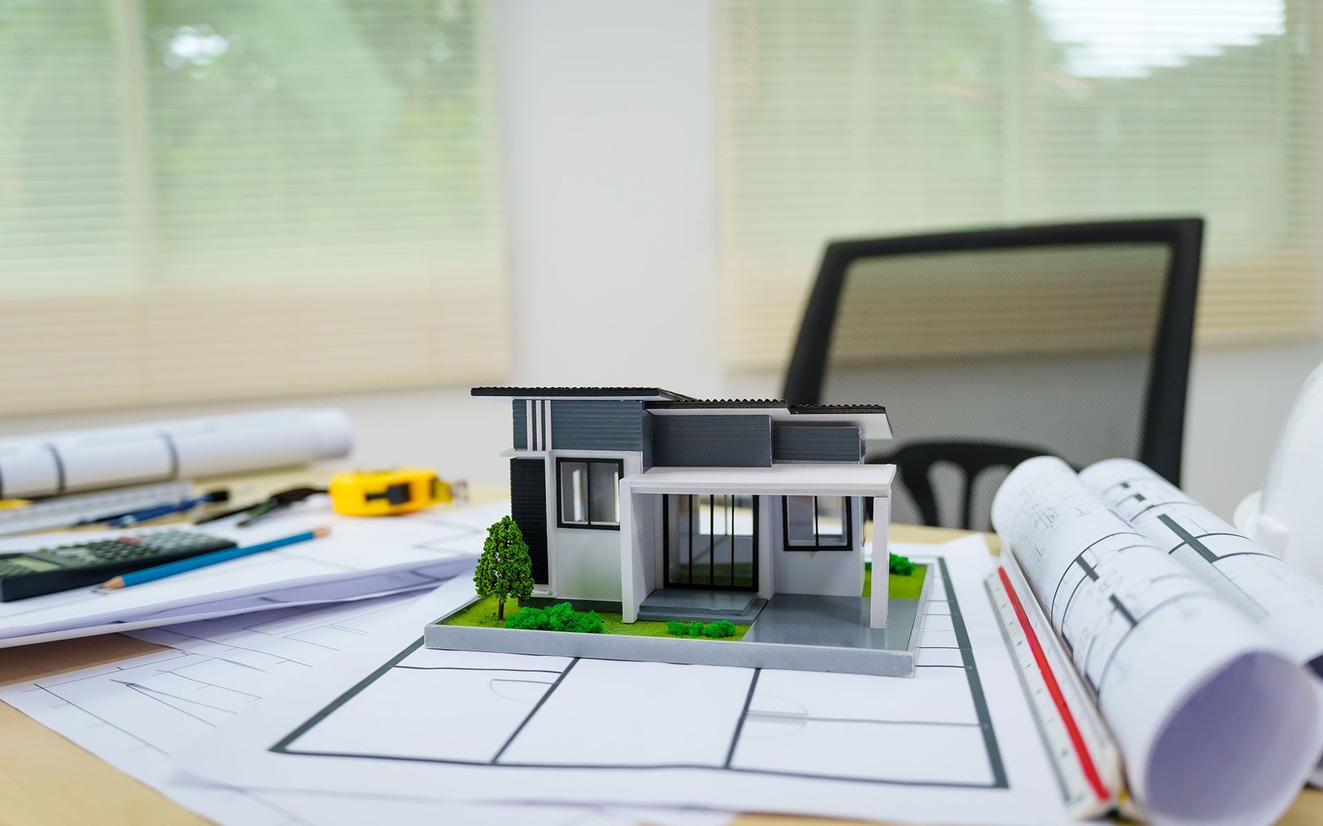 A model house is sitting on top of a blueprint on a table.