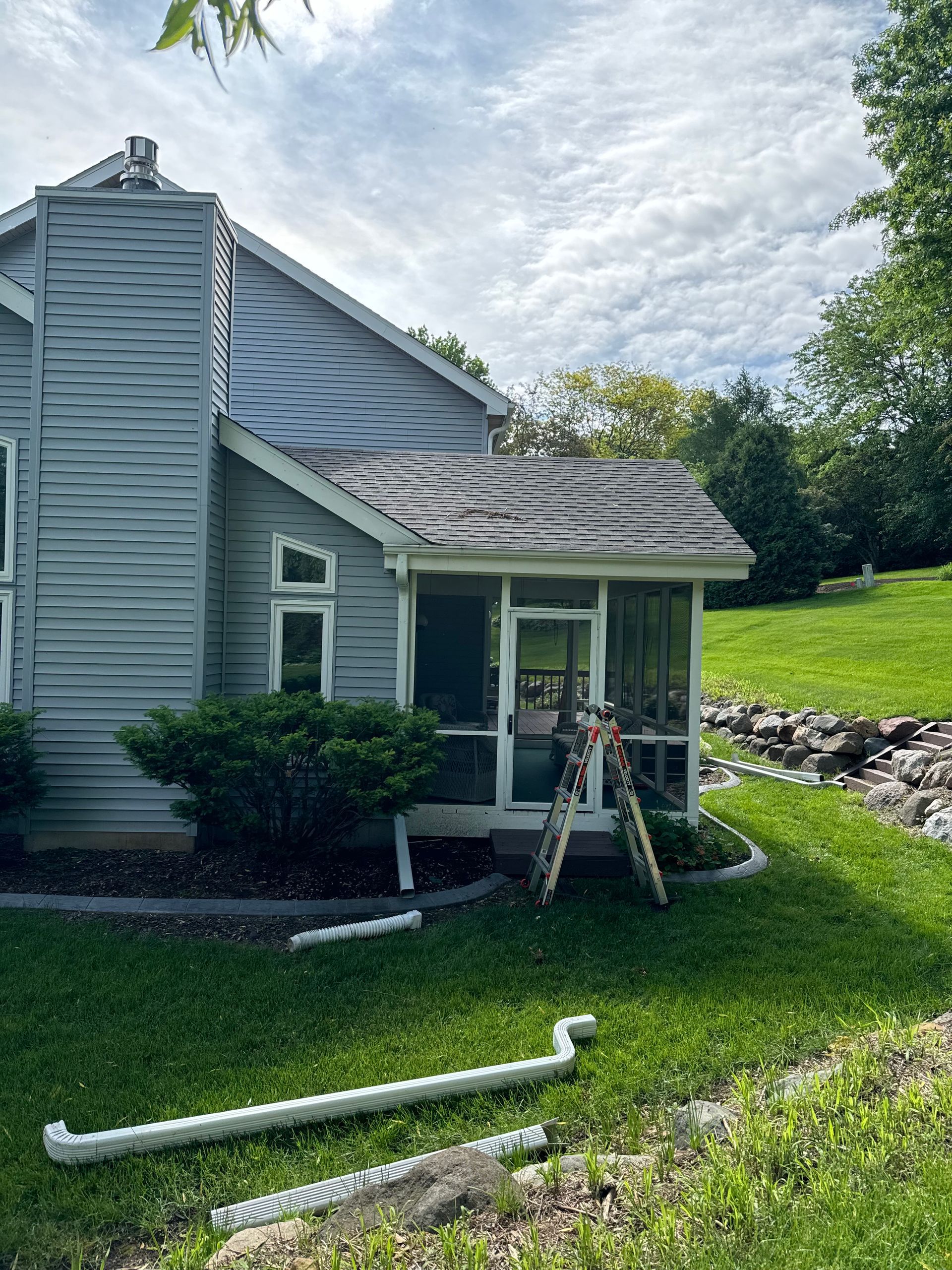 A house with a screened in porch and a ladder in front of it.