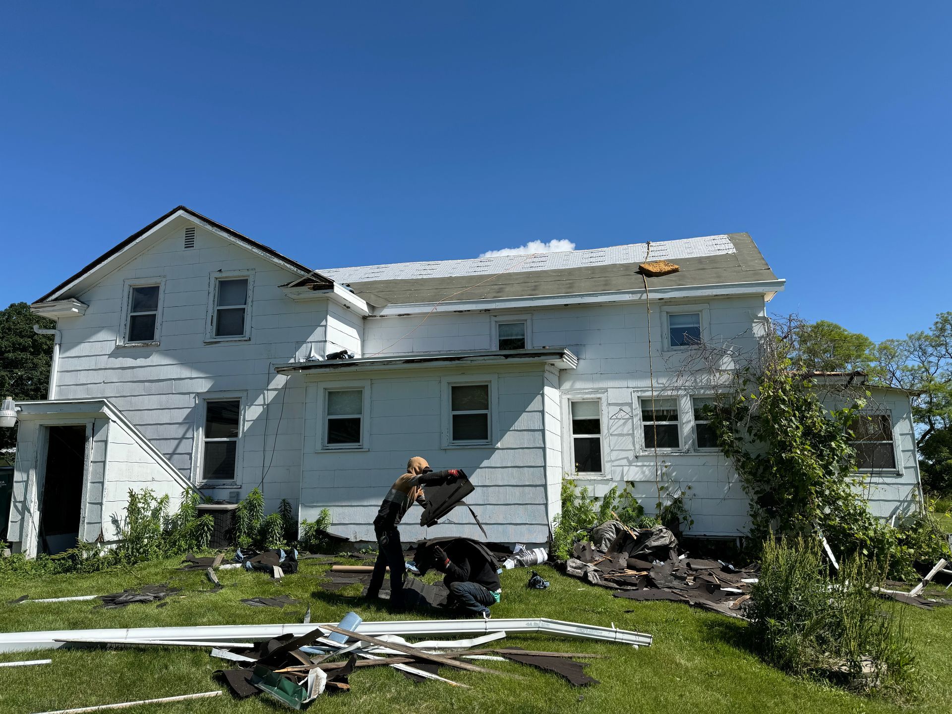 A man is working on the roof of a white house.