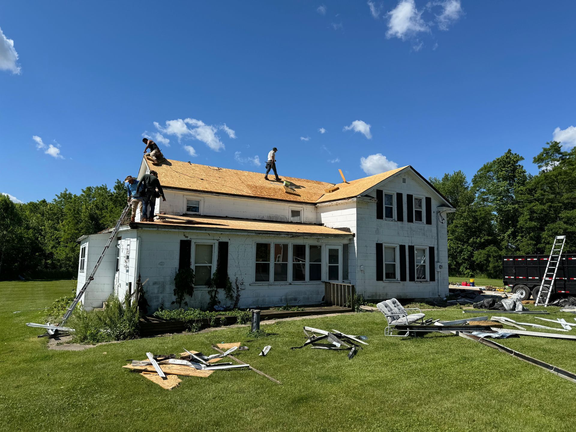 A group of people are working on the roof of a house.