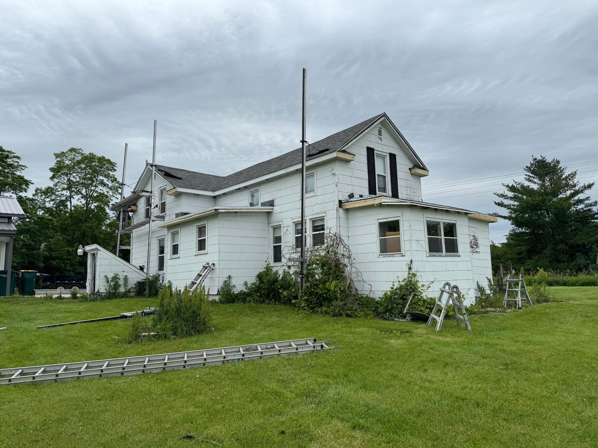 A large white house is sitting in the middle of a grassy field.