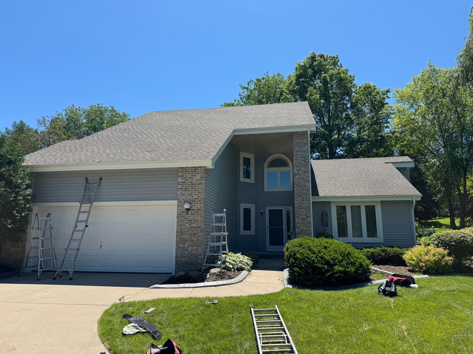 A large house with a ladder in front of it is being painted.
