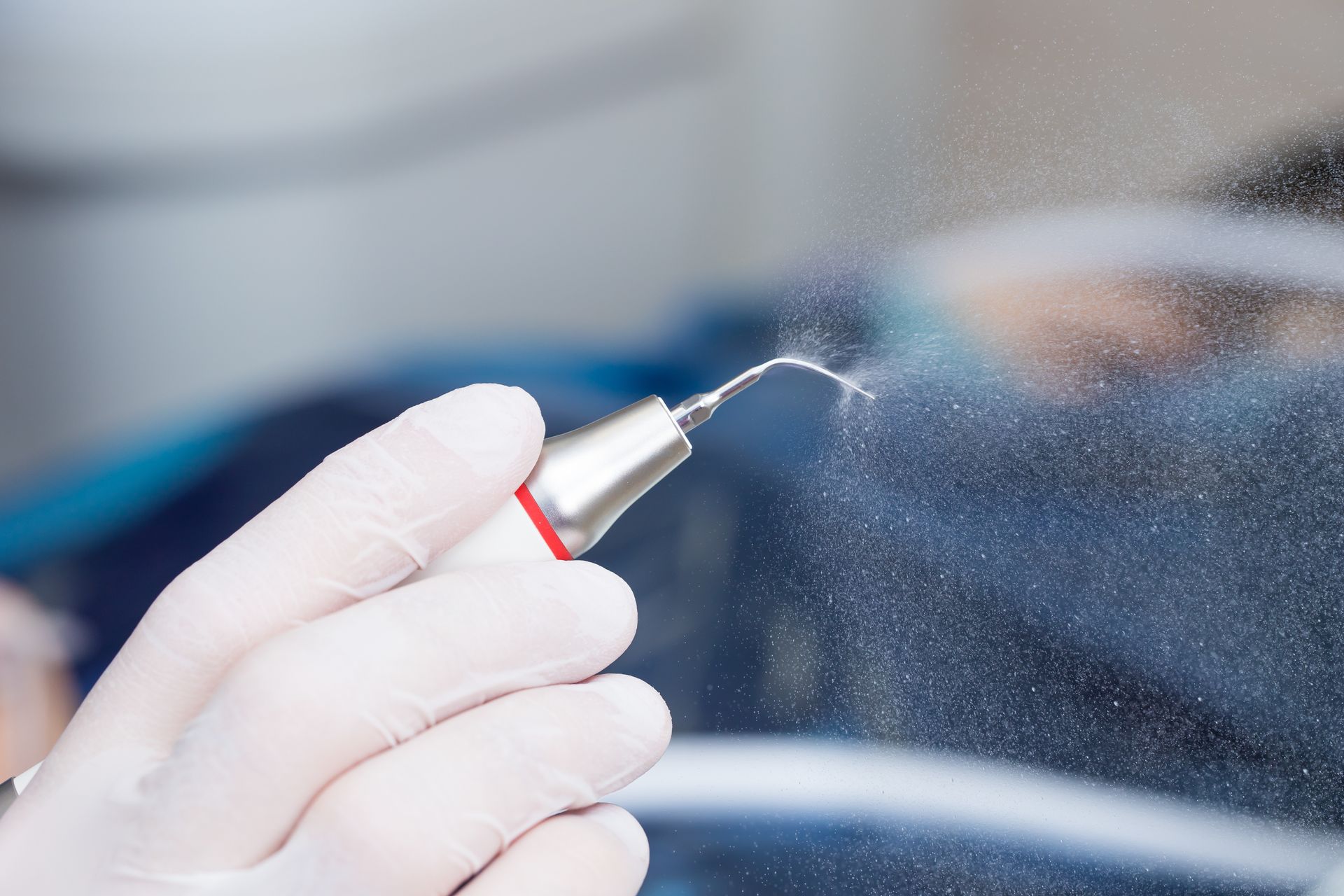 Mano guantata che utilizza un ugello spray per nebulizzare il parabrezza o la superficie di un'auto