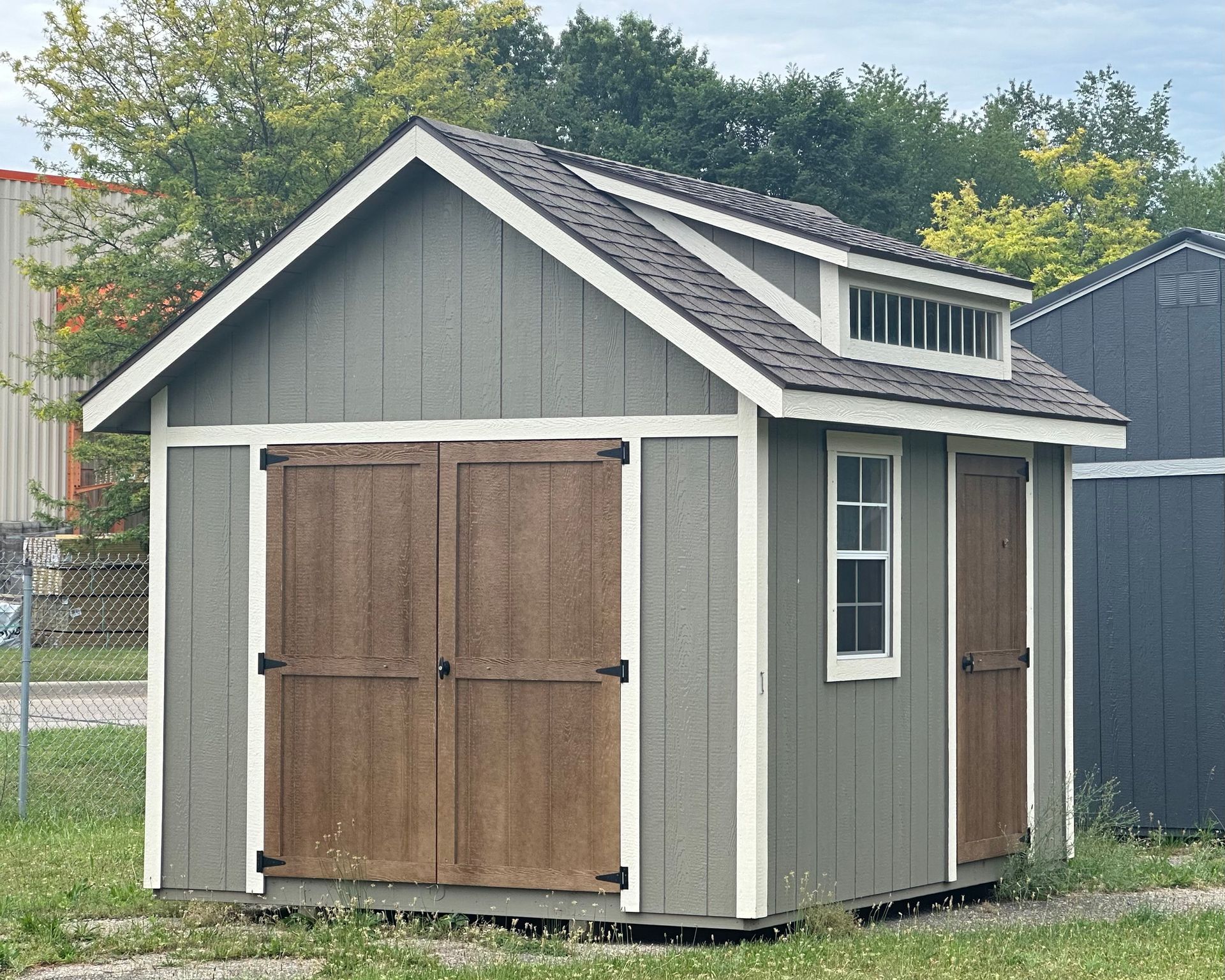 A gray shed with a brown door and a window