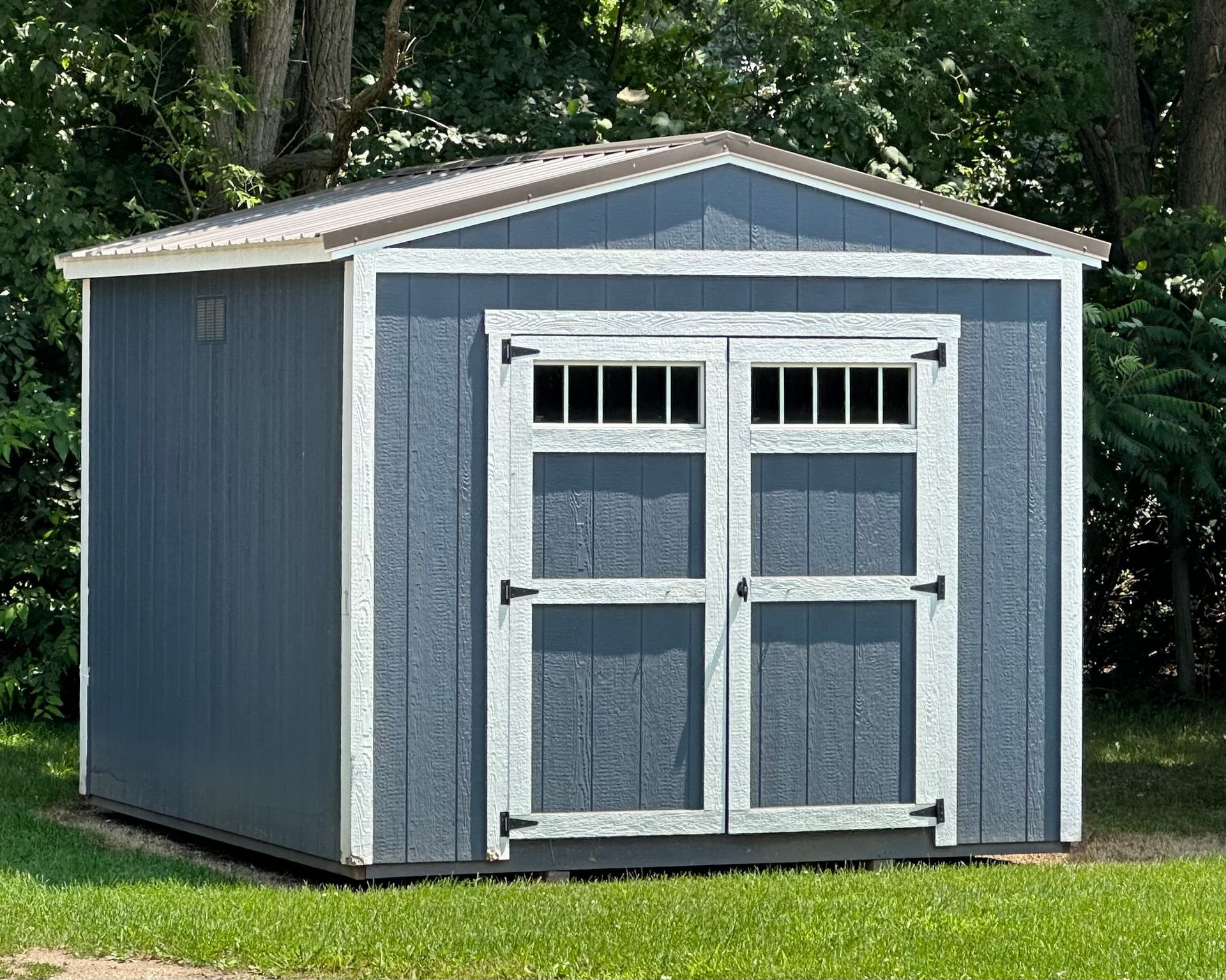 A blue and white shed is sitting on top of a lush green field.