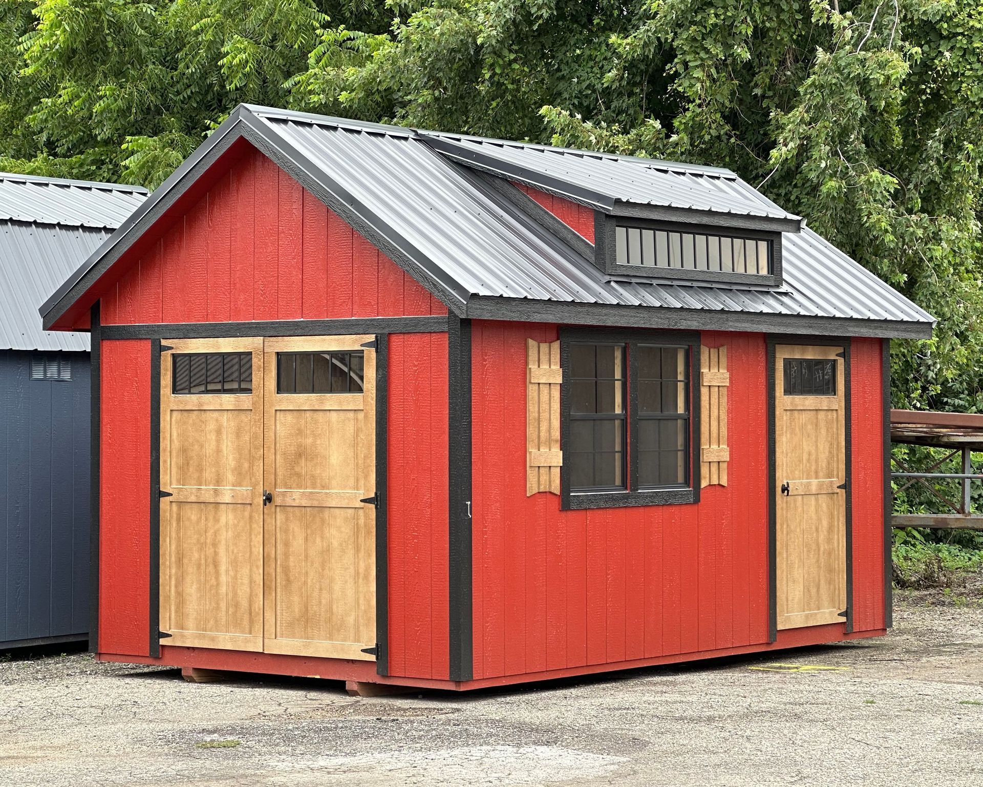 A red shed with a black roof and wooden doors.