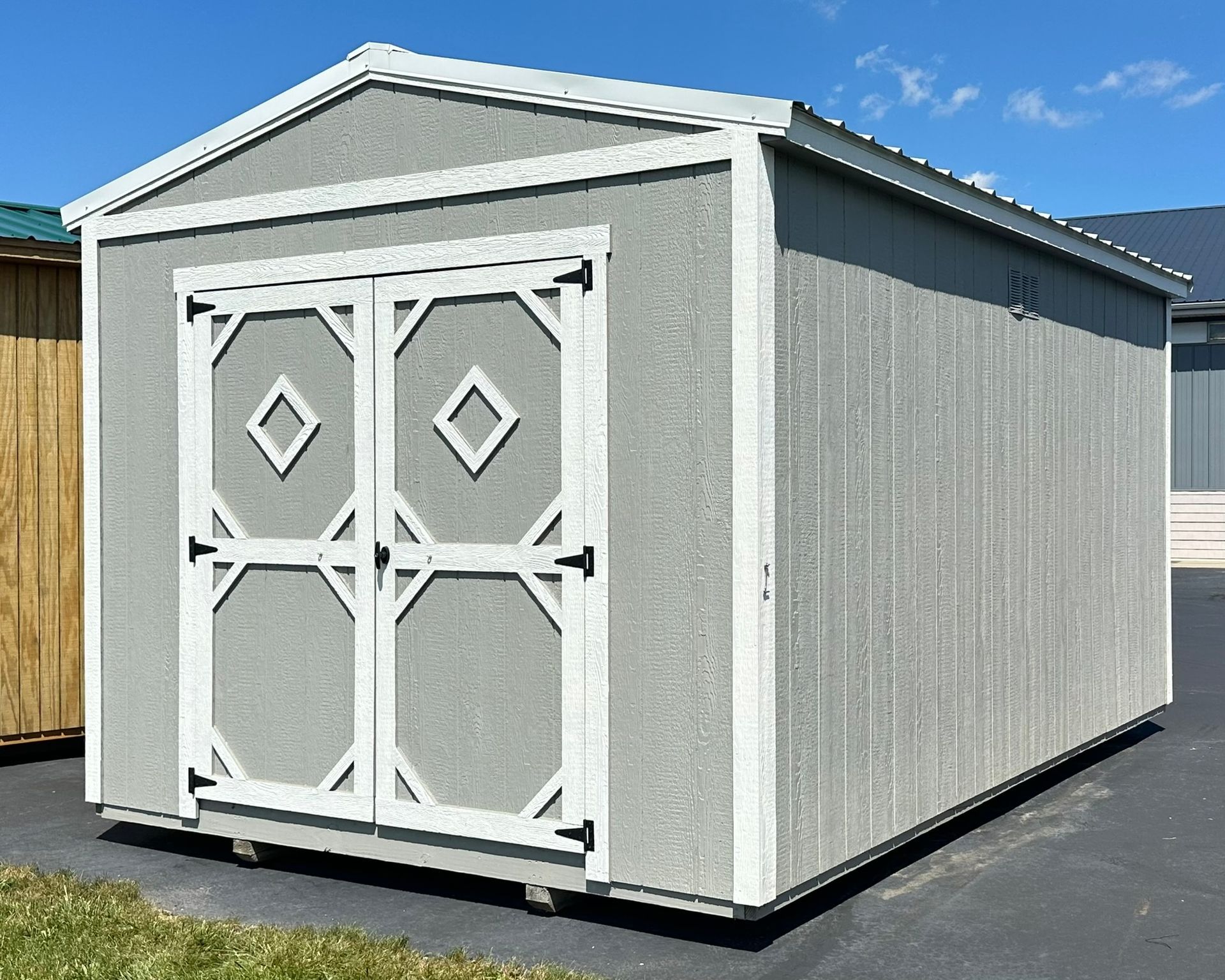 A gray and white shed with a diamond pattern on the doors.