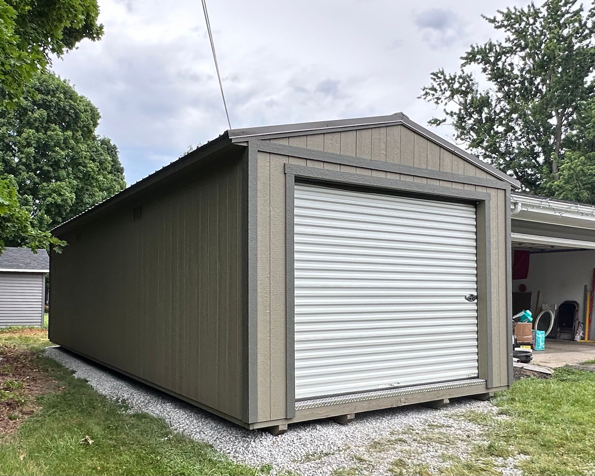 A garage with a roll up door is sitting next to a house.