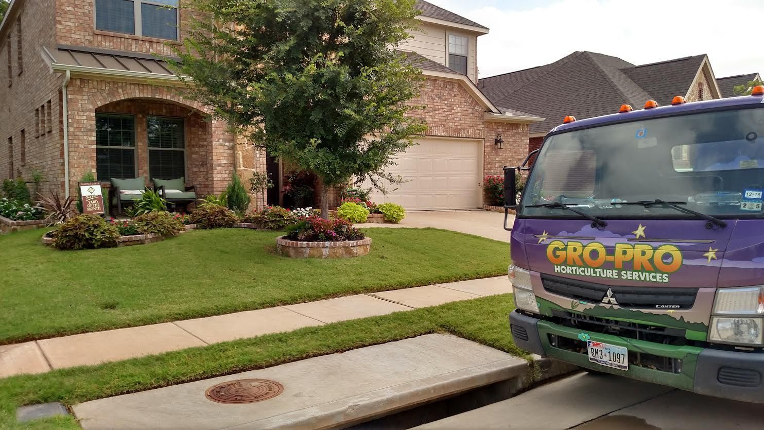 Lawn care truck parked by a suburban house with a manicured front yard