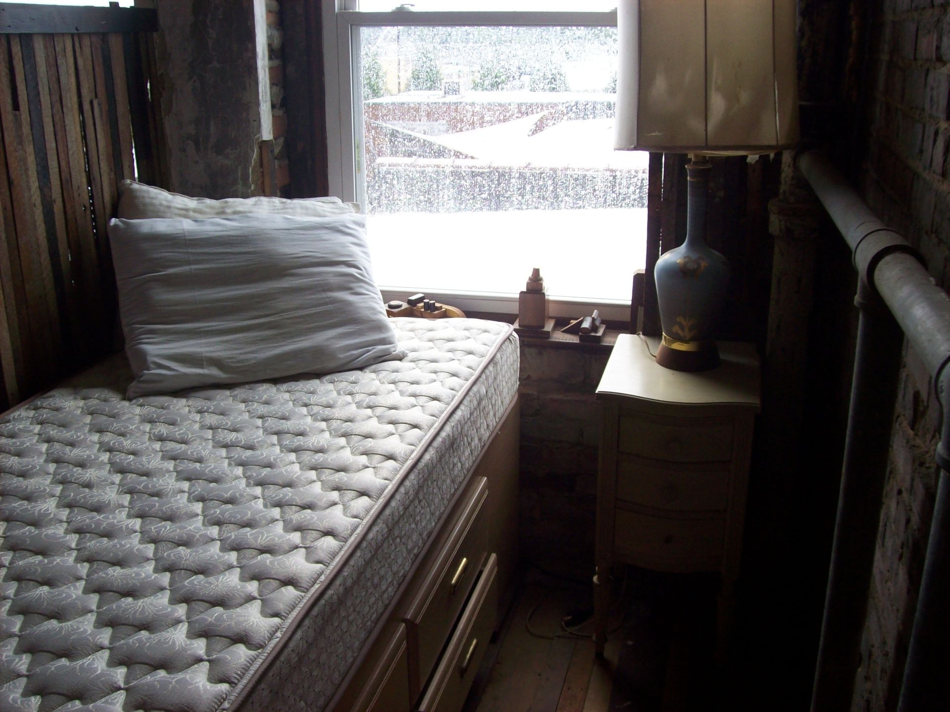 a small bedroom with a mattress and a lamp