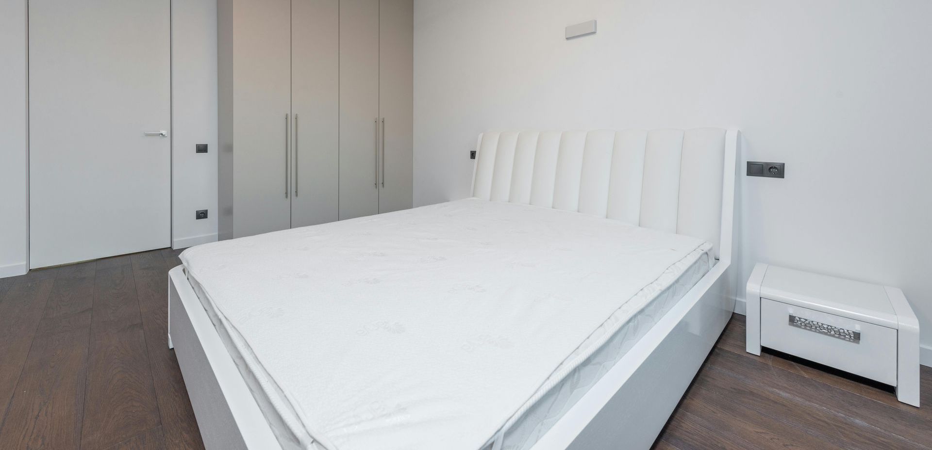 There is a bed with a white mattress in the middle of the room.