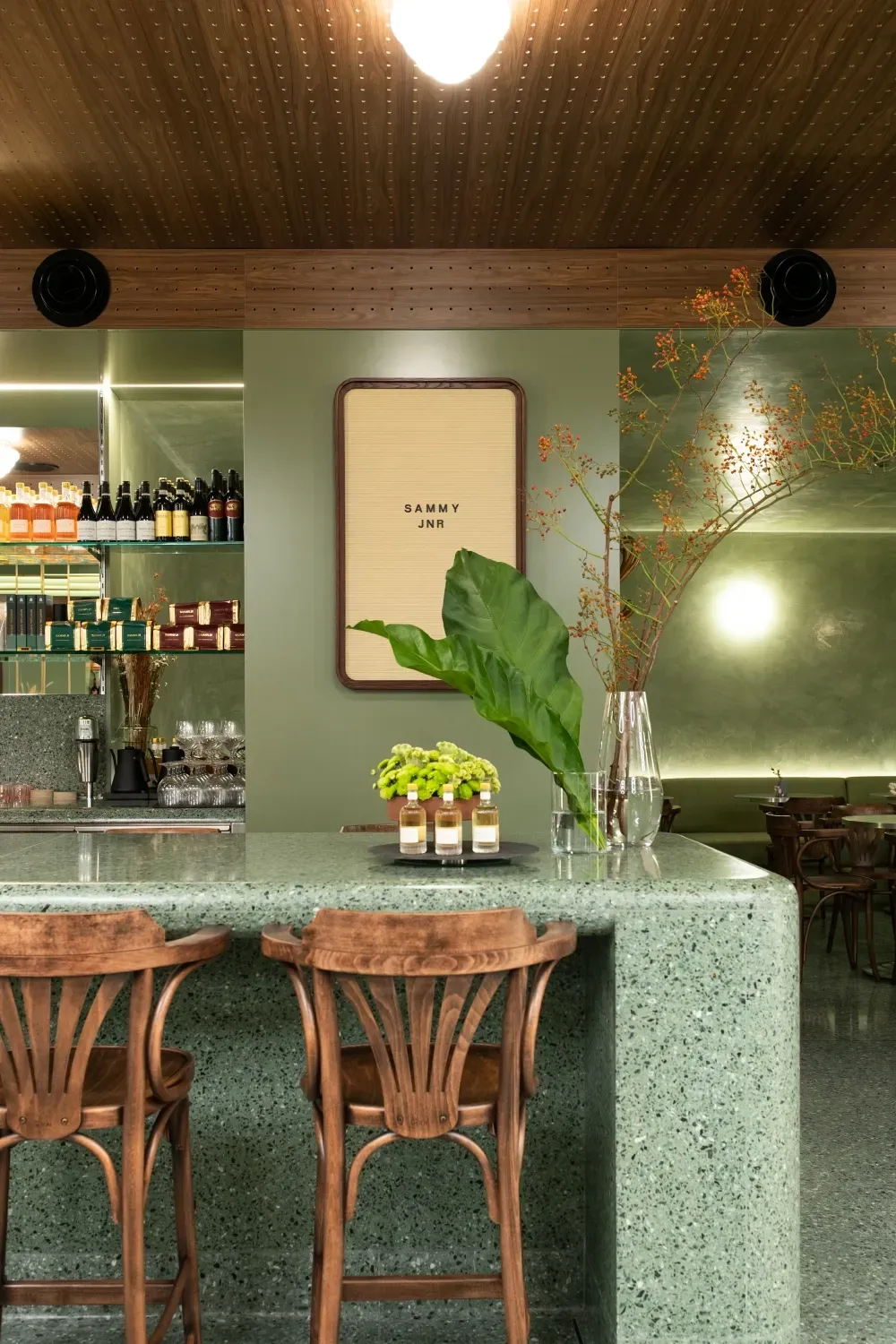 A restaurant with a green counter top and wooden chairs.